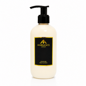 A light cream bottle with a black pump, featuring a black label with "Ancienne Ambiance London" logo and "Signature Body Lotion" in gold text. Clean and elegant design.