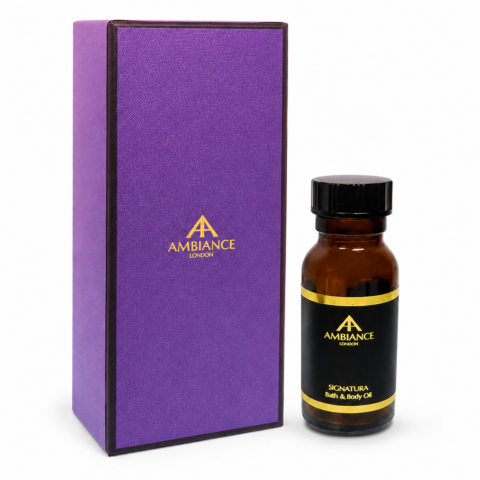 A purple box with "Ancienne Ambiance London" logo in gold beside an amber bottle labeled "Signatura Bath & Body Oil." The packaging conveys luxury and elegance.