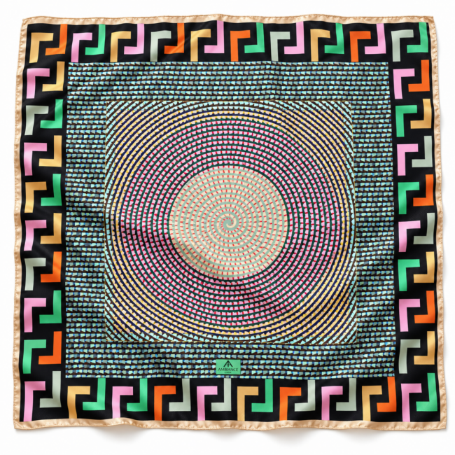 A colourful silk scarf with a central spiral pattern of small triangles in pink, green, and blue. The border features bold geometric shapes in black, pink, orange, and green, creating a vibrant, dynamic design.