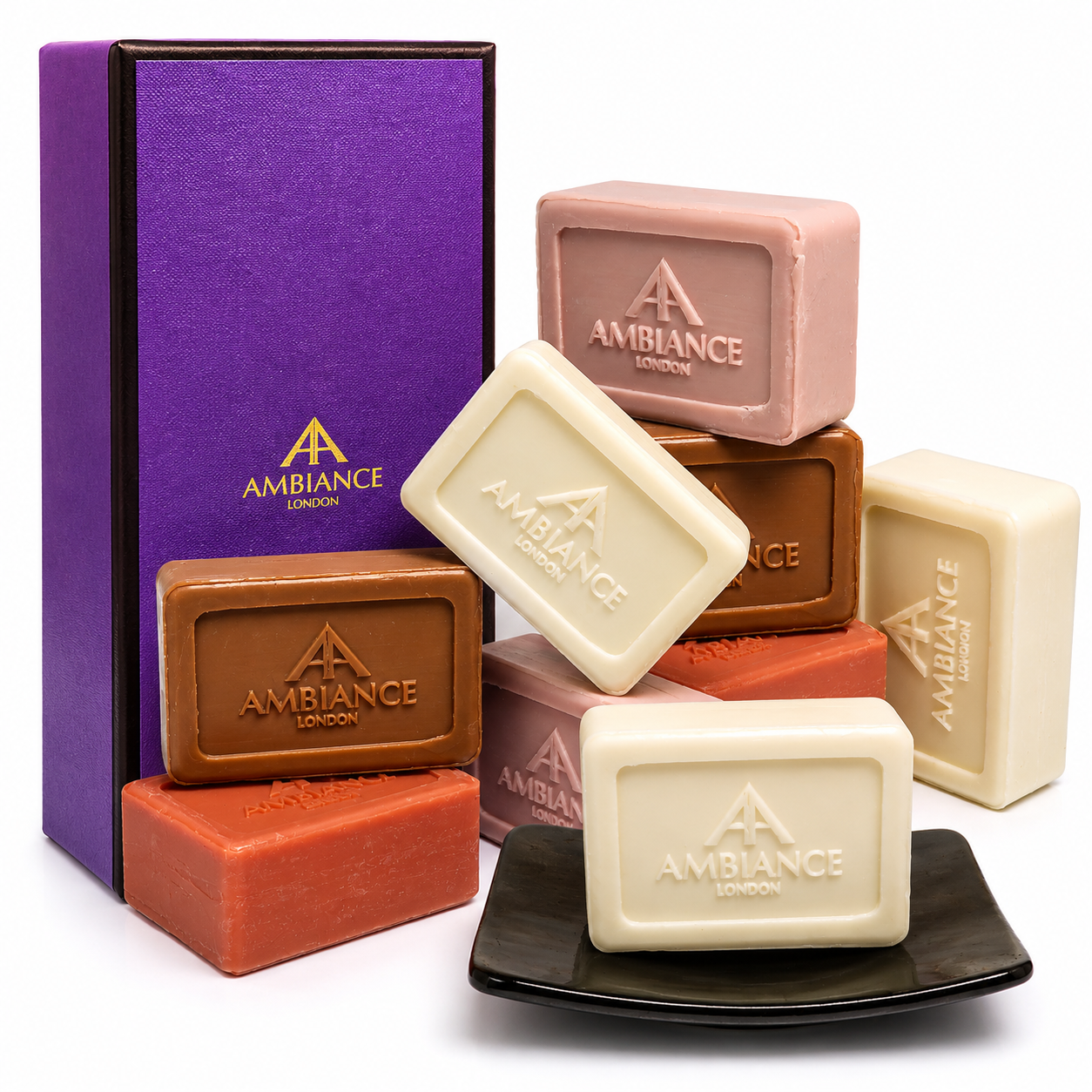 A collection of Ancienne Ambiance London soap bars in diverse colours, including white, pink, brown, and orange, arranged neatly beside a purple gift box. The scene conveys luxury and elegance.