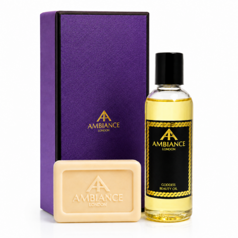 A luxurious set featuring a purple box, a bottle of Ancienne Ambiance London Goddess Beauty Oil, and a matching soap. The design conveys elegance and sophistication.