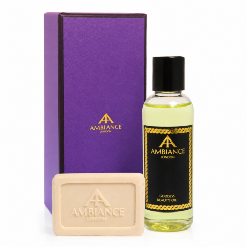 A luxurious set featuring a purple box, a bottle of Ancienne Ambiance London Goddess Beauty Oil, and a matching soap. The design conveys elegance and sophistication.