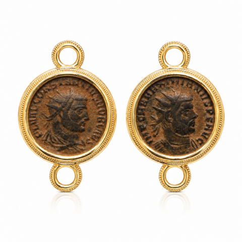 Two Ancient Roman coins set in gold round frames, each featuring a profile of an emperor. The coins have a rustic, historical look.