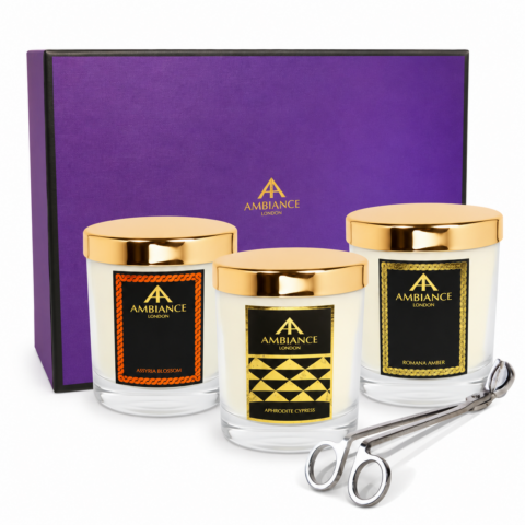Ancienne Ambiance London three-candle gift set featuring Assyria Blossom, Aphrodite Cypress and Romana Amber scented candles with gold lids, presented with a purple Ambiance London gift box and silver wick trimmer on a white background.