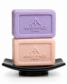 Two bars of soap are stacked on a black dish: a purple bar on top and a peach one beneath, both embossed with "AMBIANCE LONDON," on a white background.