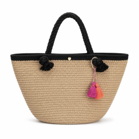 A basket tote bag with black handles and trim features two colourful tassels—pink and orange—hanging from a gold keyring. The design is stylish and summery.