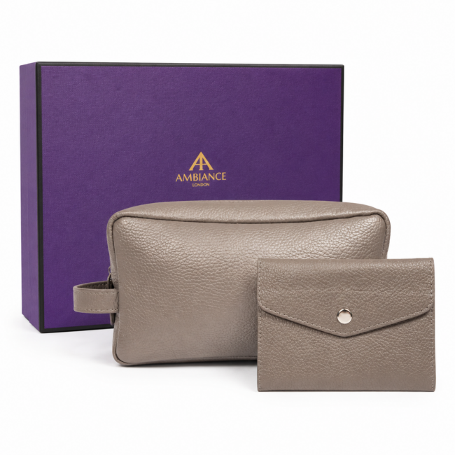 A grey leather pouch and wallet sit in front of a purple box with gold "Ancienne Ambiance London" logo. The image conveys luxury and elegance.