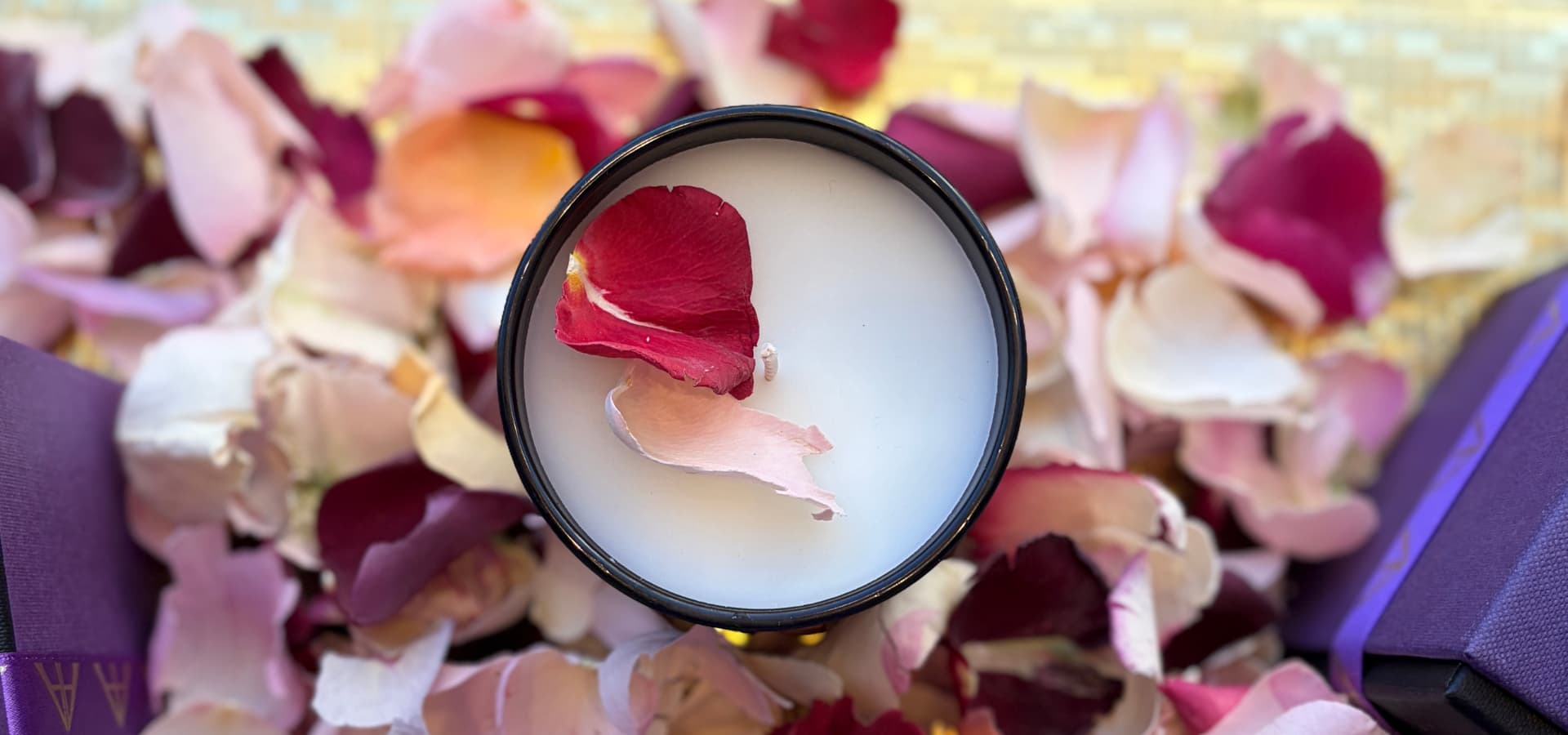 A close-up of a candle surrounded by colourful rose petals, creating a soothing and elegant ambience.