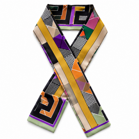 A silk twilly scarf with a geometric pattern featuring black, white, purple, green, and orange shapes. The scarf is arranged in a criss-cross design.