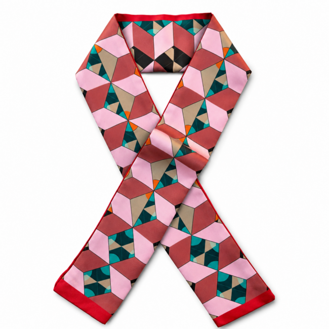 A colourful silk twilly scarf features a geometric pattern of interconnected cubes in shades of pink, red, beige, and teal, with a red border, evoking a modern, artistic feel.