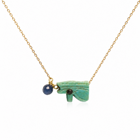 A delicate gold chain necklace features an ancient Egyptian faience Eye of Horus pendant, accompanied by a blue sapphire, creating an elegant look.
