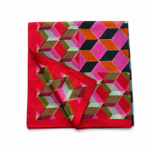 A vibrant geometric-patterned sarong scarf featuring interlocking hexagons in pink, red, green, and orange hues, with a folded corner revealing layers.