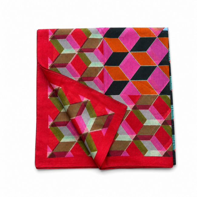 A vibrant geometric-patterned sarong scarf featuring interlocking hexagons in pink, red, green, and orange hues, with a folded corner revealing layers.