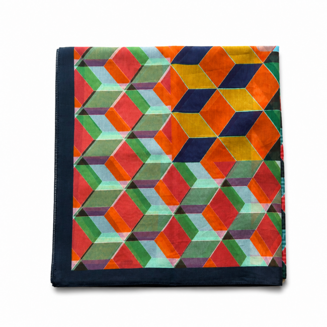 A vibrant geometric pattern on a folded scarf, featuring interlocking colourful cubes in red, blue, green, and yellow with a dark border.