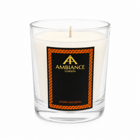 Clear Ancienne Ambiance London glass candle with a white wax interior. The black label reads "Assyria Blossom" in gold letters, surrounded by an orange patterned border.
