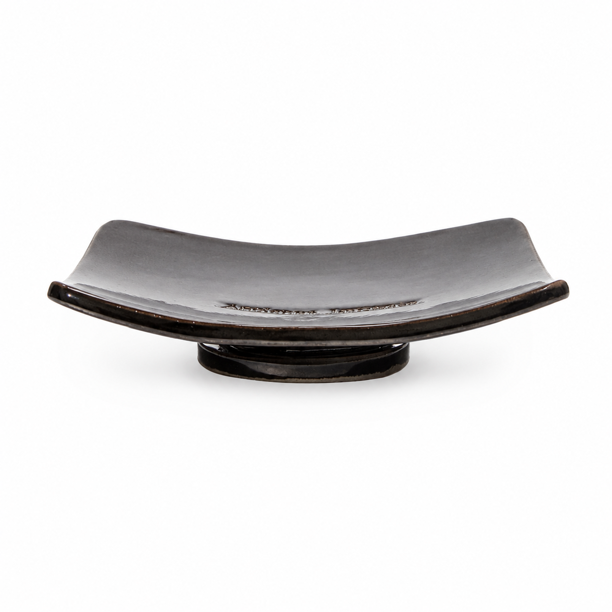 A sleek, rectangular black ceramic soap dish with slightly upturned edges sits on a small pedestal base, against a white background.