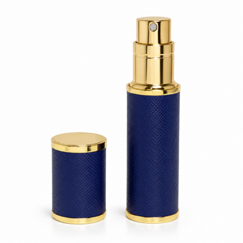 Luxury travel perfume atomiser set featuring dark blue textured surfaces with gold accents. The small bottle has a spray nozzle; the cap is beside it. Elegant and classy design.