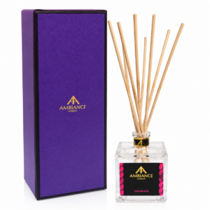 A purple box next to a square glass diffuser bottle with wooden reeds. The bottle label reads "Ancienne Ambiance London" and "Damask Rose" in gold and pink.