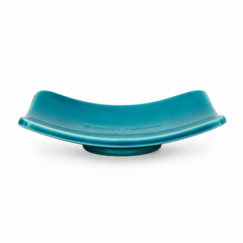 Curved, rectangular teal ceramic soap dish with a glossy finish, resting on a round base against a plain white background. Minimalist and elegant design.