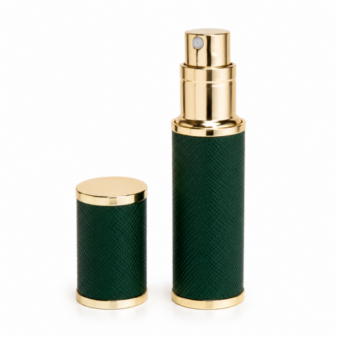 Luxurious green travel perfume atomiser with a textured finish and gold accents beside its matching cap. Elegant and sophisticated design on a white background.
