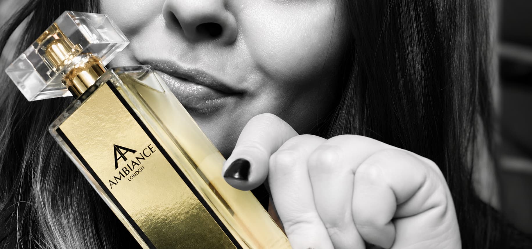 A woman holds a gold Ancienne Ambiance London perfume bottle near her face. The tone is elegant and luxurious.