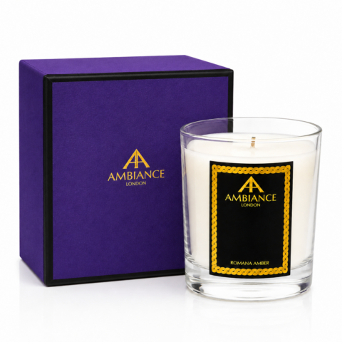 Glass Ancienne Ambiance London candle marked "Romana Amber" with an elegant black and gold label sits beside a matching purple and black box. Luxurious and sophisticated tone.