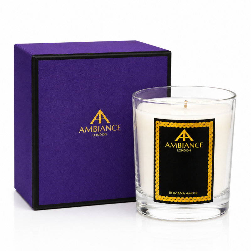 Glass Ancienne Ambiance London candle marked "Romana Amber" with an elegant black and gold label sits beside a matching purple and black box. Luxurious and sophisticated tone.