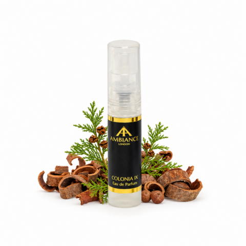 A sample perfume bottle labeled "Ancienne Ambiance London Colonia IX" stands among sandalwood shavings and cedar leaves, suggesting a natural, fresh scent.