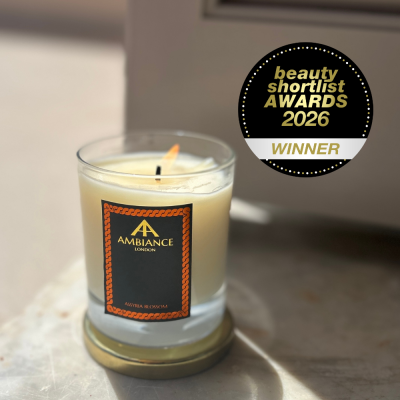 A lit Ancienne Ambiance London candle labeled "Assyria Blossom" on a marble surface. Beside it, a "Beauty Shortlist Awards 2026 Winner" badge. Peaceful ambiance.