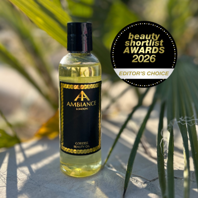 A bottle of Ancienne Ambiance London Goddess Beauty Oil is displayed outdoors, surrounded by green leaves and sunlight. A badge reads "Beauty Shortlist Awards 2026, Editor's Choice."